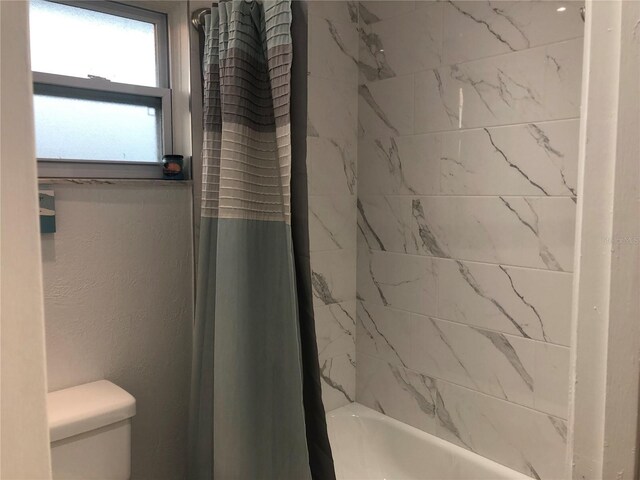 bathroom with toilet and shower / tub combo with curtain