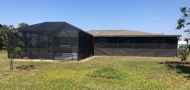 back of property featuring glass enclosure, an outdoor pool, and a yard