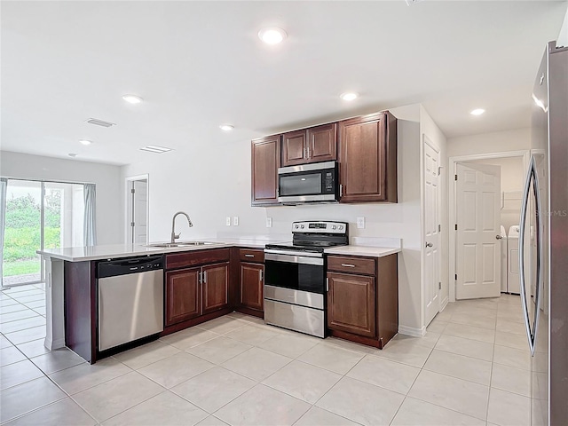 kitchen with appliances with stainless steel finishes, dark brown cabinets, sink, kitchen peninsula, and light tile patterned floors