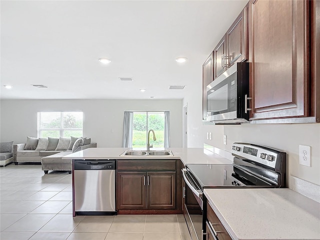 kitchen with sink, kitchen peninsula, stainless steel appliances, and light tile patterned floors