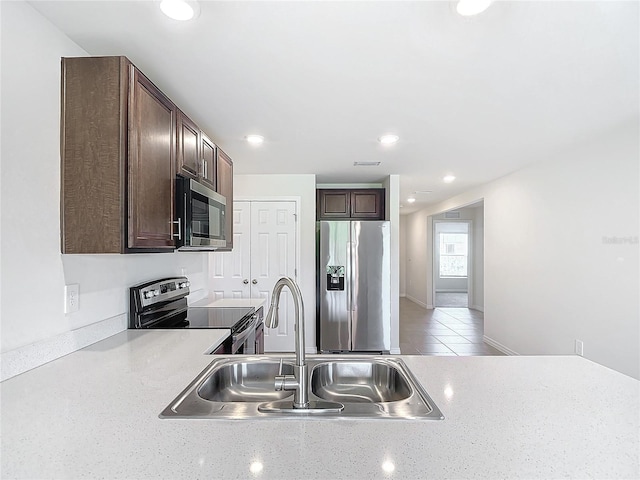 kitchen featuring sink, light tile patterned flooring, dark brown cabinets, and stainless steel appliances