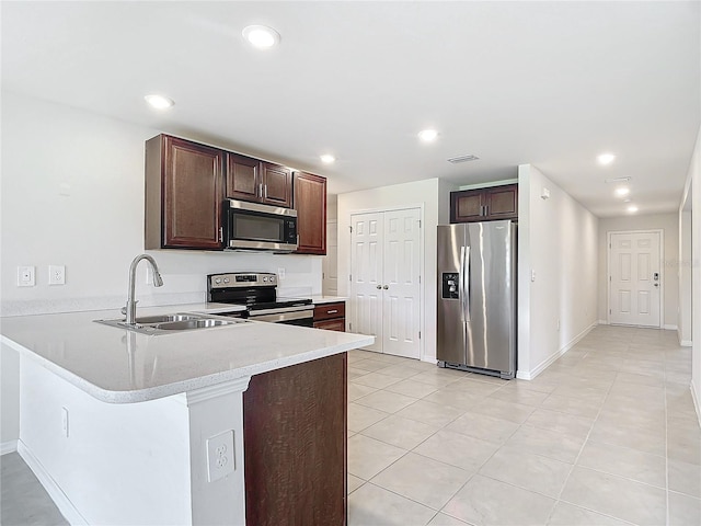 kitchen with stainless steel appliances, dark brown cabinets, sink, kitchen peninsula, and light tile patterned floors