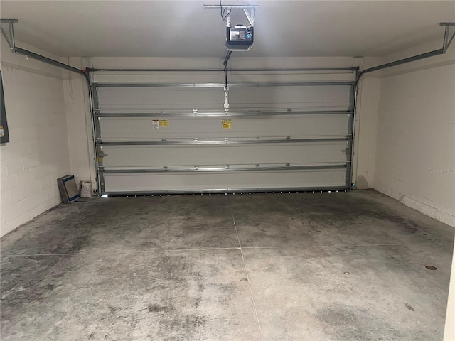 garage featuring a garage door opener and concrete block wall