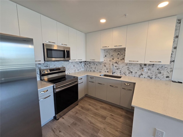 kitchen featuring white cabinets, sink, appliances with stainless steel finishes, and hardwood / wood-style floors