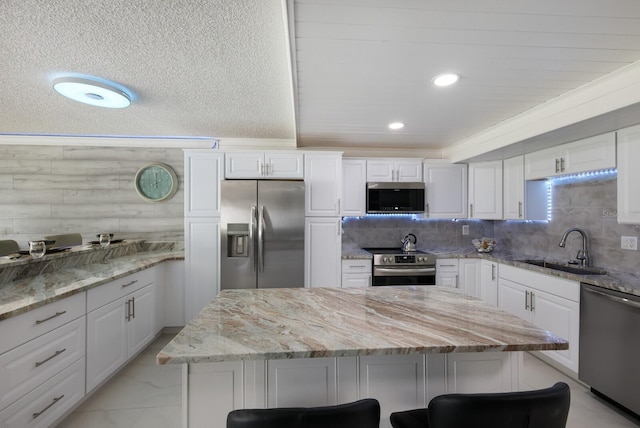 kitchen featuring sink, stainless steel appliances, white cabinets, and a kitchen breakfast bar