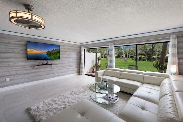 living room with plenty of natural light, a textured ceiling, and wooden walls