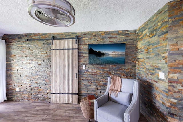 unfurnished room featuring hardwood / wood-style floors, a textured ceiling, and a barn door