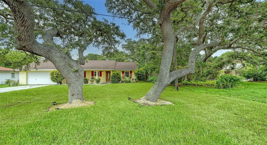 ranch-style house featuring a garage, concrete driveway, and a front lawn