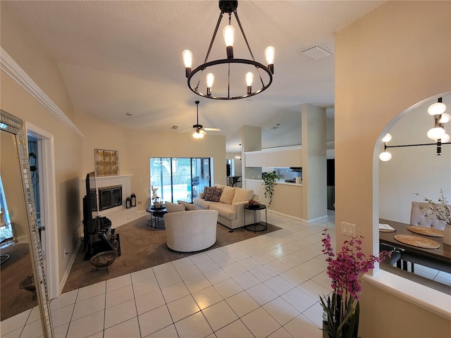 tiled living room featuring a fireplace, high vaulted ceiling, a textured ceiling, ceiling fan with notable chandelier, and built in shelves