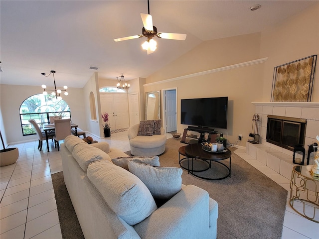 tiled living room with vaulted ceiling, ceiling fan with notable chandelier, and a fireplace