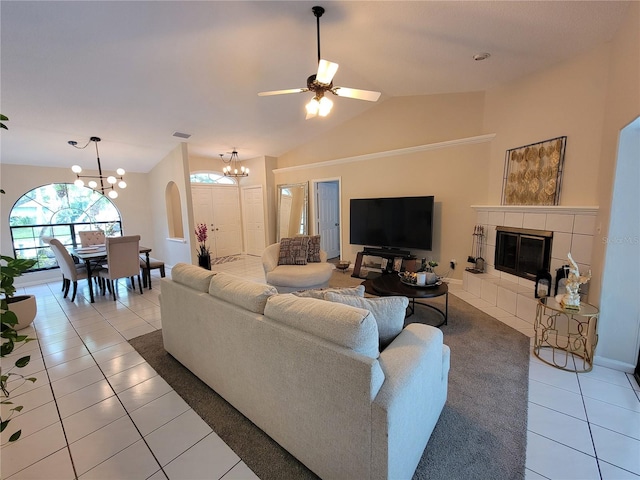 living room featuring vaulted ceiling, tile patterned floors, ceiling fan with notable chandelier, and a tile fireplace