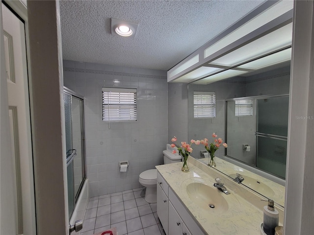 full bathroom with a textured ceiling, enclosed tub / shower combo, tile patterned flooring, vanity, and toilet