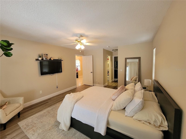 bedroom featuring ceiling fan, multiple windows, hardwood / wood-style floors, and a textured ceiling