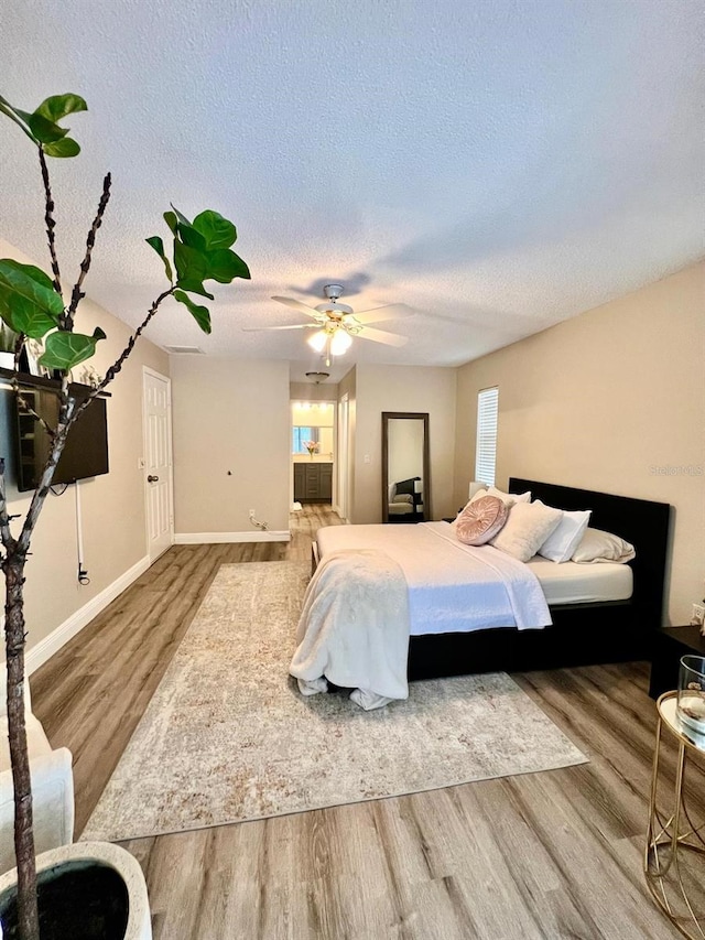 bedroom with ceiling fan, wood-type flooring, and a textured ceiling