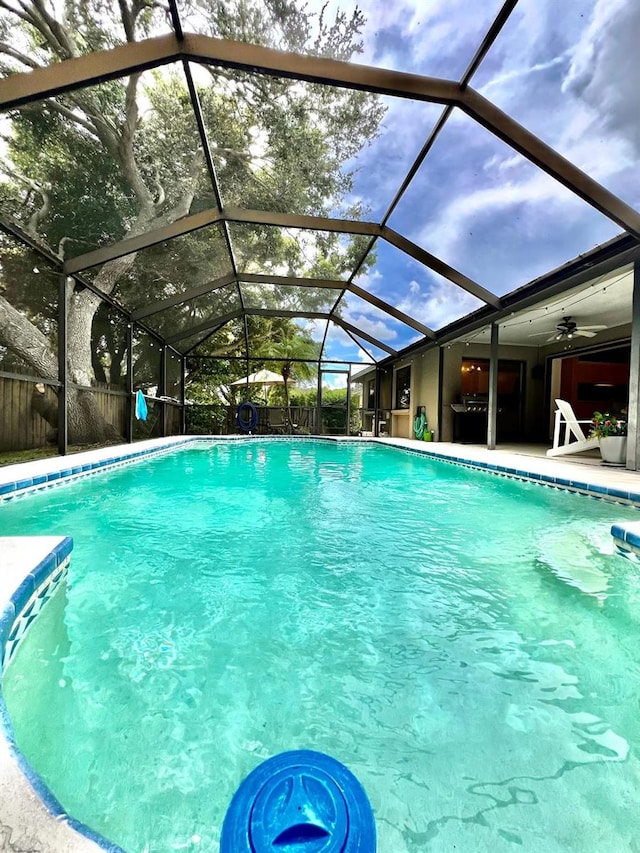 view of swimming pool featuring ceiling fan, a lanai, and a patio