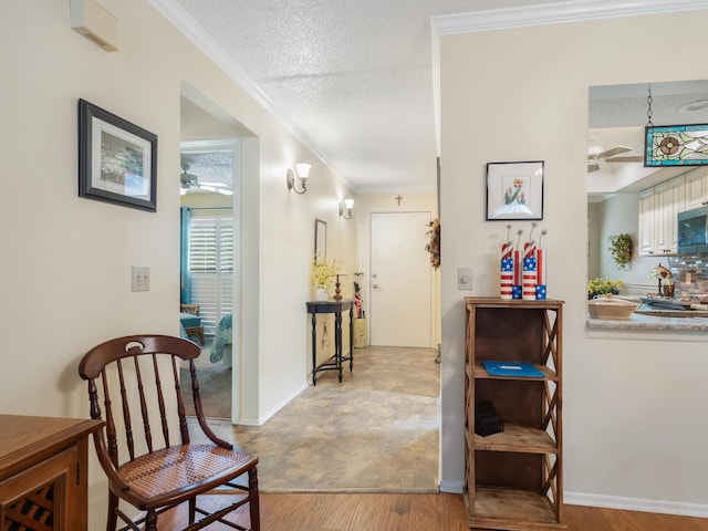 corridor with crown molding, a textured ceiling, and light hardwood / wood-style flooring