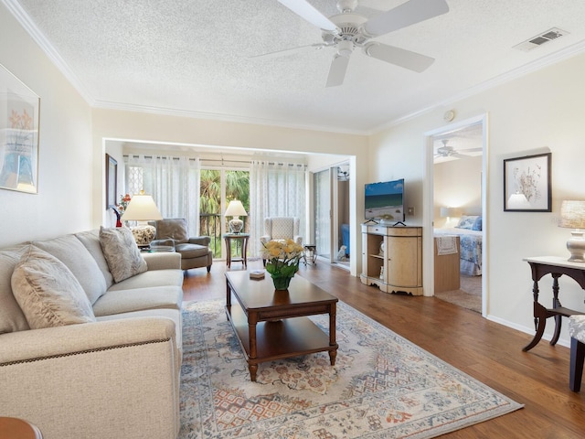 living room featuring ornamental molding, hardwood / wood-style floors, ceiling fan, and a textured ceiling