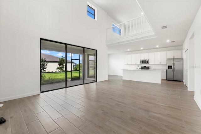 unfurnished living room featuring a towering ceiling and a wealth of natural light