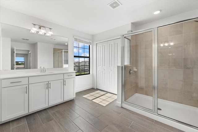 bathroom featuring a shower with door and vanity