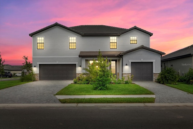 view of front of home with a garage and a lawn