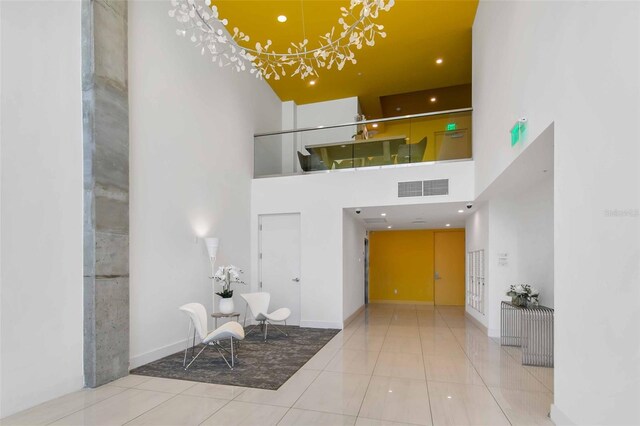 tiled foyer entrance with an inviting chandelier and a towering ceiling