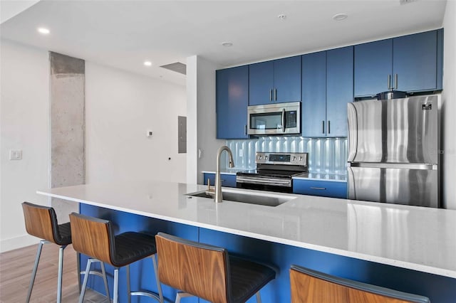 kitchen featuring sink, wood-type flooring, blue cabinetry, and stainless steel appliances