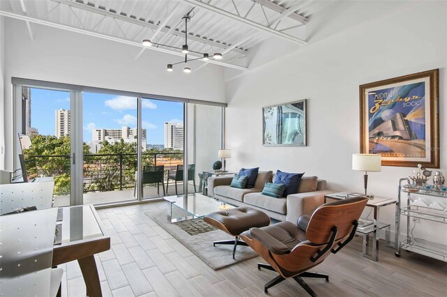 living room featuring light hardwood / wood-style floors, a notable chandelier, and a towering ceiling