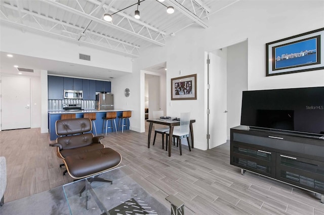 living room featuring light wood-type flooring and a towering ceiling