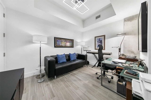 office space featuring light hardwood / wood-style floors and a raised ceiling