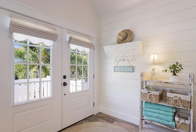 doorway to outside featuring hardwood / wood-style floors, wood walls, and lofted ceiling