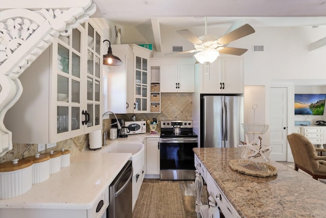 kitchen with vaulted ceiling, stainless steel appliances, white cabinetry, and light stone counters