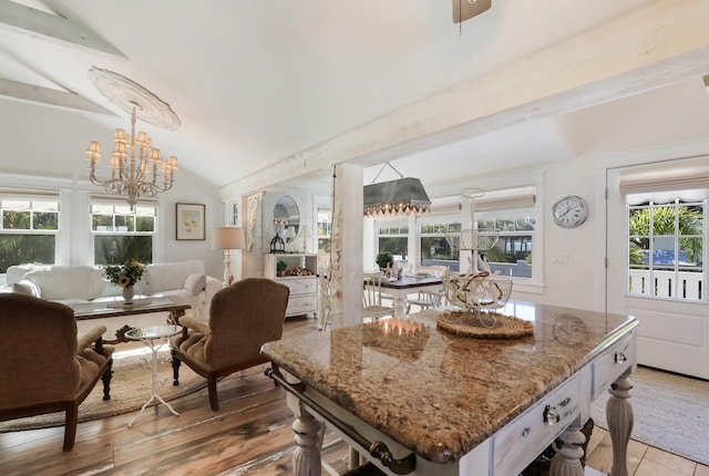 kitchen featuring hanging light fixtures, an inviting chandelier, light stone counters, vaulted ceiling, and white cabinets