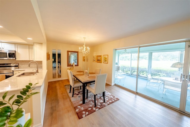 dining area with light hardwood / wood-style flooring, sink, and an inviting chandelier