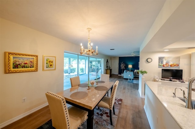 dining area with ceiling fan with notable chandelier and dark hardwood / wood-style floors