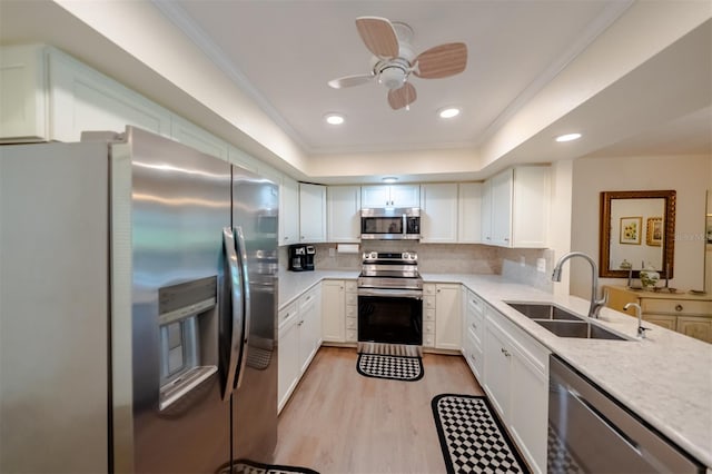 kitchen with light wood-type flooring, backsplash, ceiling fan, appliances with stainless steel finishes, and sink