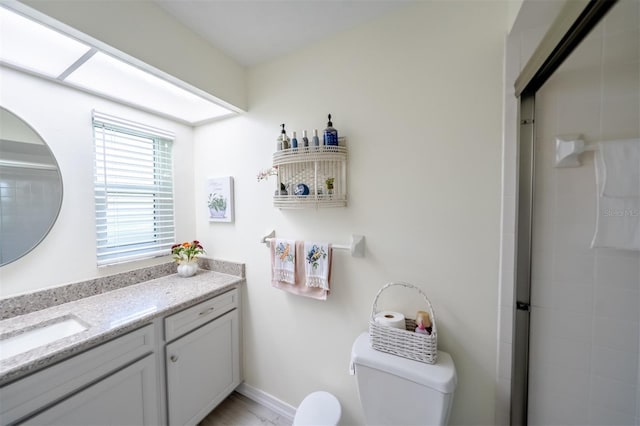 bathroom featuring vanity, a shower with door, and toilet