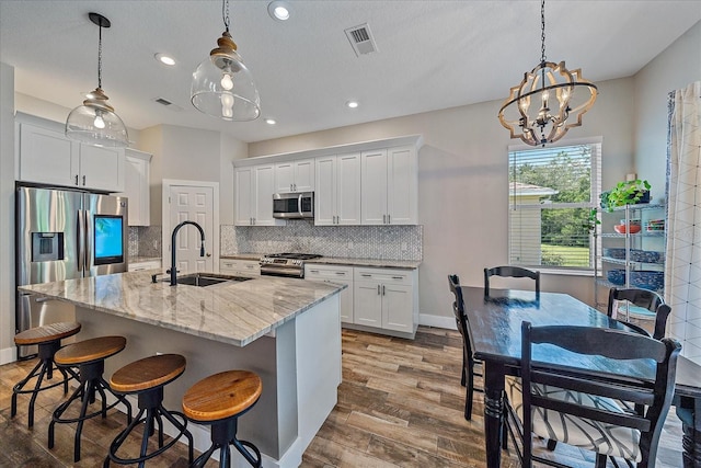 kitchen with white cabinets, sink, a kitchen island with sink, and stainless steel appliances