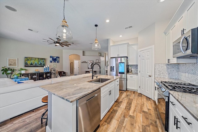 kitchen with sink, a kitchen breakfast bar, a kitchen island with sink, white cabinets, and appliances with stainless steel finishes