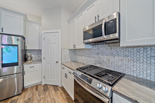 kitchen with backsplash, white cabinetry, and stainless steel appliances