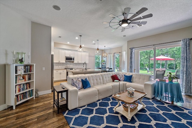 living room featuring ceiling fan, dark hardwood / wood-style flooring, sink, and a textured ceiling