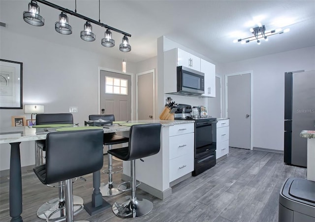 kitchen featuring white cabinetry, decorative light fixtures, hardwood / wood-style floors, and stainless steel appliances