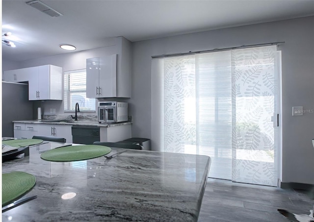 kitchen featuring white cabinetry, light stone countertops, and hardwood / wood-style floors