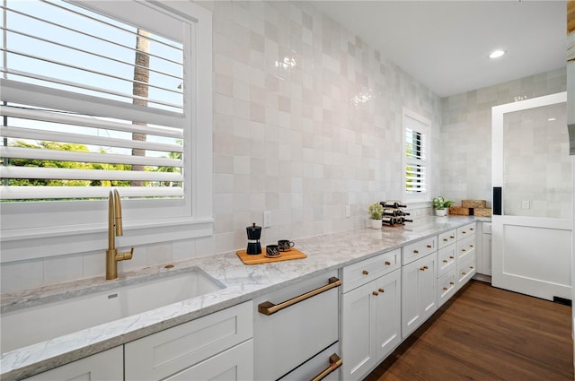 kitchen featuring dark hardwood / wood-style flooring, white cabinetry, sink, and light stone countertops