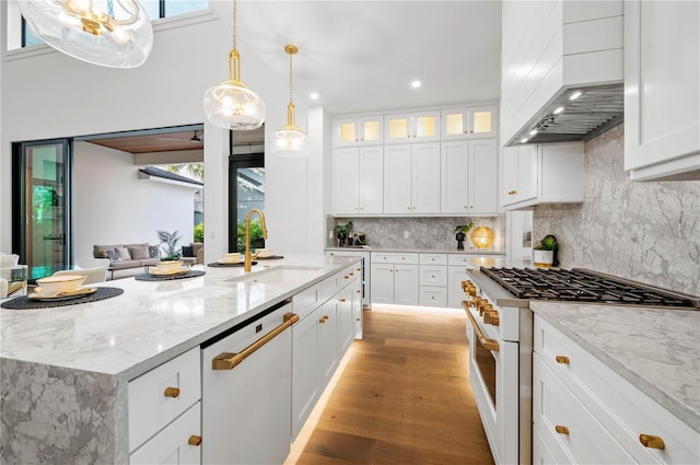 kitchen with white appliances, premium range hood, white cabinets, sink, and a kitchen island