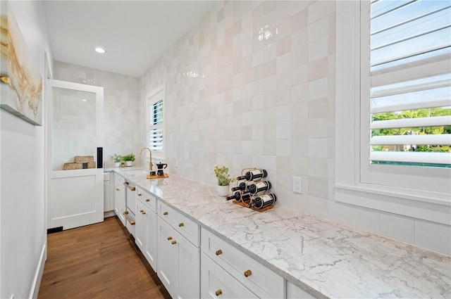 kitchen featuring a wealth of natural light, white cabinetry, dark hardwood / wood-style flooring, and light stone counters