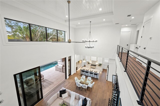 living room with hardwood / wood-style flooring, a notable chandelier, ornamental molding, and a tray ceiling