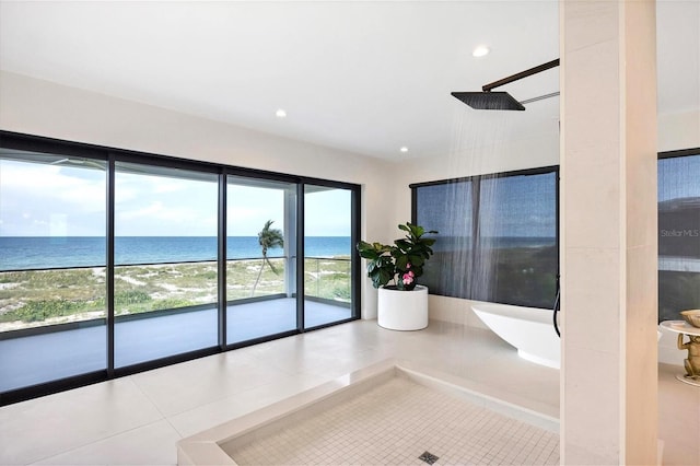 interior space featuring tile patterned floors, a water view, and a beach view