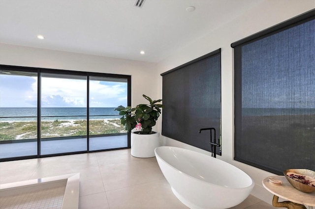 bathroom featuring a view of the beach, tile patterned floors, a water view, and a bathing tub