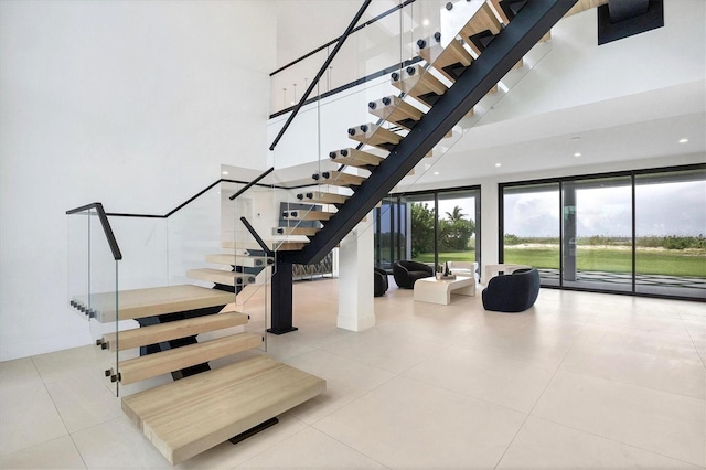 stairs featuring tile patterned flooring and a high ceiling