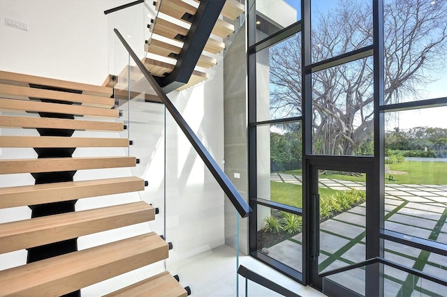 stairway with a wall of windows, a towering ceiling, and plenty of natural light